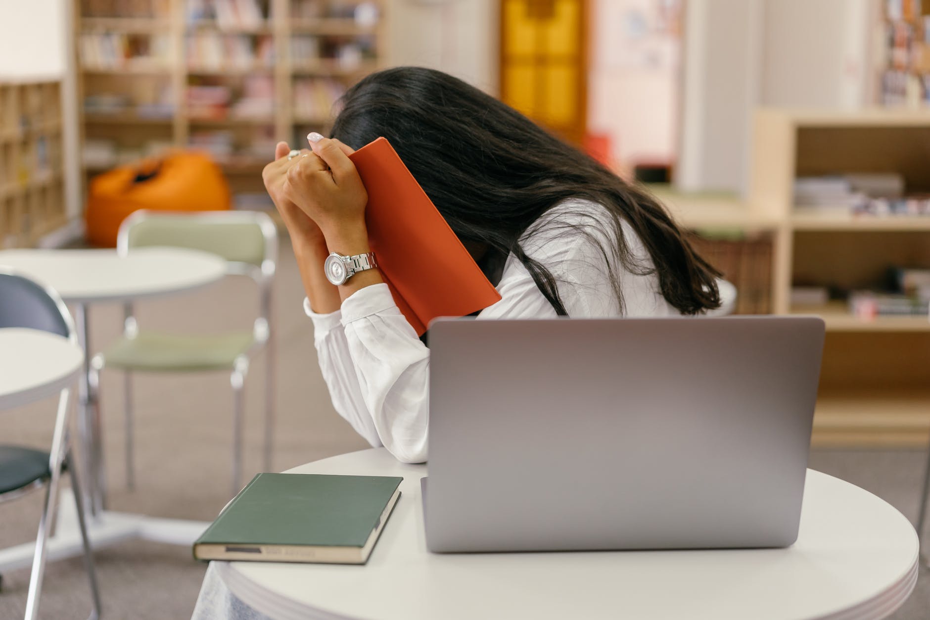 shy and introverted college student hiding behind a book at the library