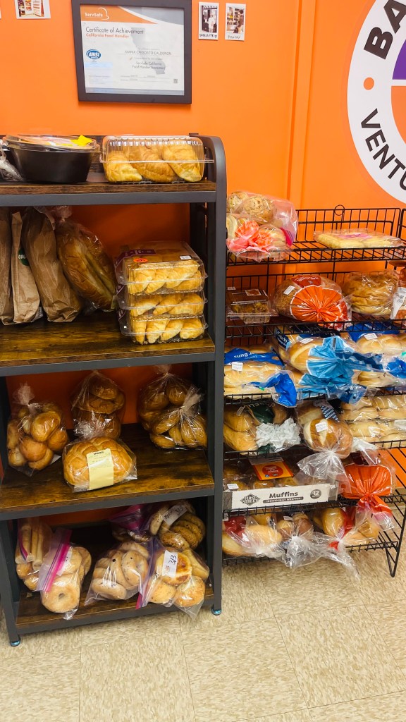 Ventura College Basic Needs Center bread and bakery shelves stocked with bagels, loaves, muffins, and pastries for student distribution.